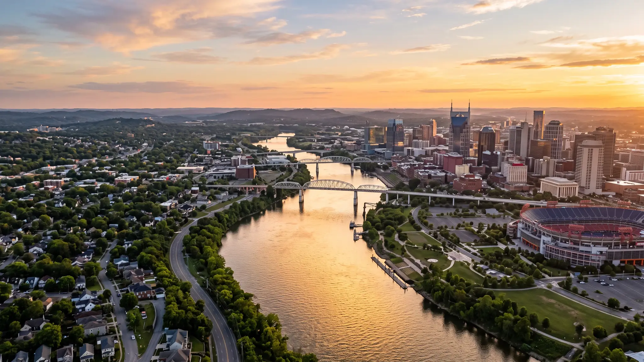 Aerial view of the Cumberland River winding past the Nashville skyline and Middle Tennessee farmland at sunset